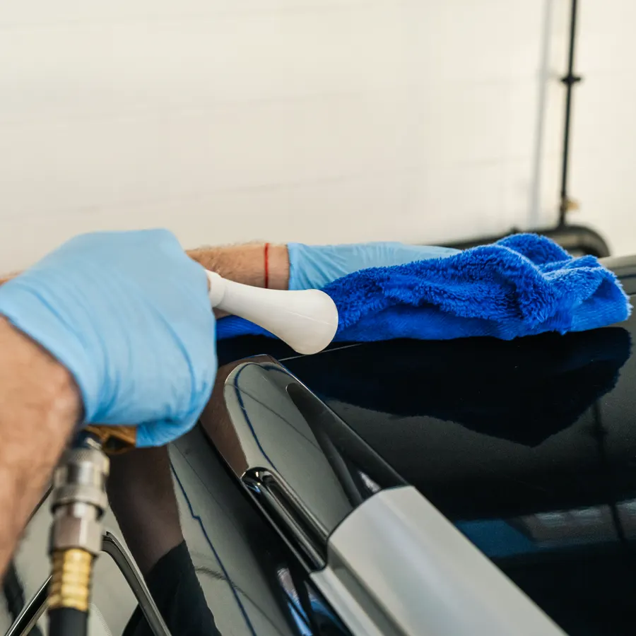 Hand drying a black car with a microfibre towel