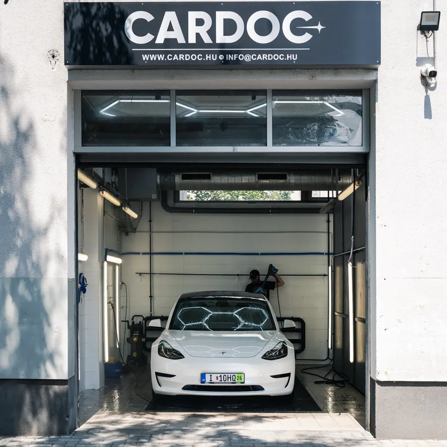 White Tesla Model 3 under the CARDOC sign